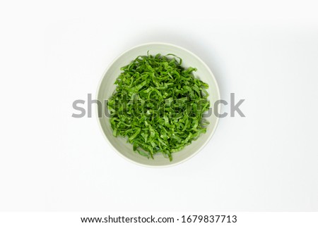 Chopped spinach in a bowl isolated on white background, top view Royalty-Free Stock Photo #1679837713