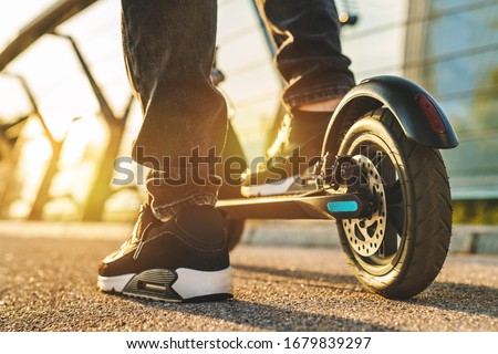 Close up of young man ready to discover the urban city at sunset with electric scooter or e-scooter Royalty-Free Stock Photo #1679839297