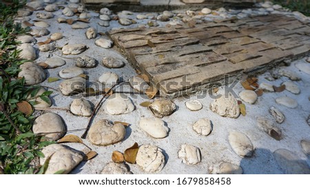 Garden landscaping of walk way or pathway made up of slab of tiled stones and pebbles. White pebbles and stones walkway decoration with circular tiles or carved rocks.  