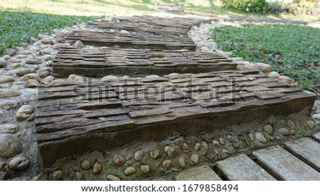 Garden landscaping of walk way or pathway made up of slab of tiled stones and pebbles. White pebbles and stones walkway decoration with circular tiles or carved rocks.  