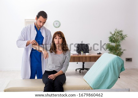 Young male doctor checking woman joint flexibility