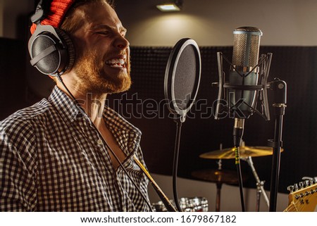 professional caucasian singer man sing in recording studio. handsome guy enjoy performing music, emotional singer with microphone and headset