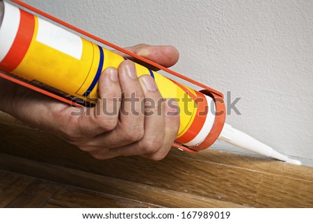 Caulking silicone from cartridge on wooden batten. Royalty-Free Stock Photo #167989019