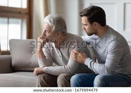 Loving young man embrace comfort upset elderly gray-haired dad suffering from depression or problems, caring adult grown-up son hug caress support mature father feeling lonely distressed at home Royalty-Free Stock Photo #1679894479