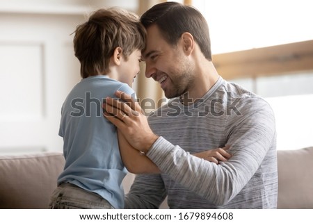 Loving young father and cute little preschooler son hug cuddle enjoying family weekend at home together, caring dad and small boy child embrace sharing bonding moment relaxing in living room