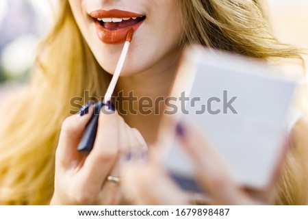 Closeup photo, girl draws lips with red lipstick.