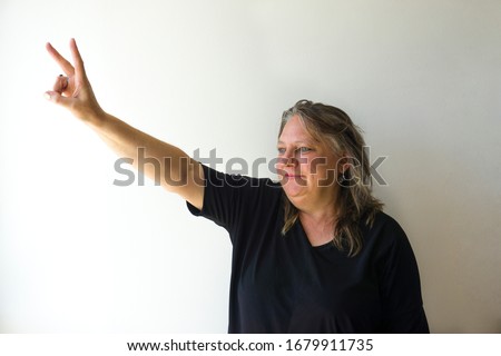Old woman doing number two gesture on white background. Gesturing number 2. Peace or victory symbol. Number two / letter V in sign language. Being second concept. Hand counting two. Space for ad text.