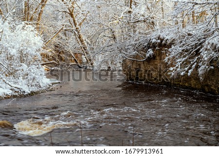 Winter landscape with river Vizla going through the snowy forest park.