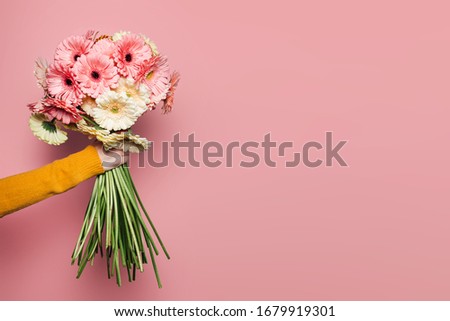 Young woman with flowers on pink pure background