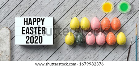 easter eggs and lightbox with message HAPPY EASTER 2020 surrounded by water color boxes on wooden background