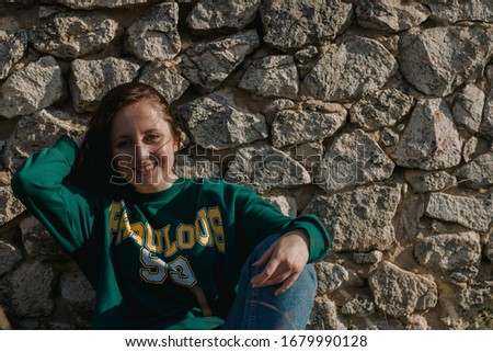 smiling girl sits on a background of an old stone wall