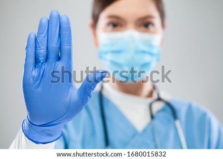 Young female UK ICU doctor hand gesturing STOP Coronavirus COVID-19 disease global pandemic outbreak,please help not spread virus worldwide,stay safe home keep social physical distance isolation Royalty-Free Stock Photo #1680015832