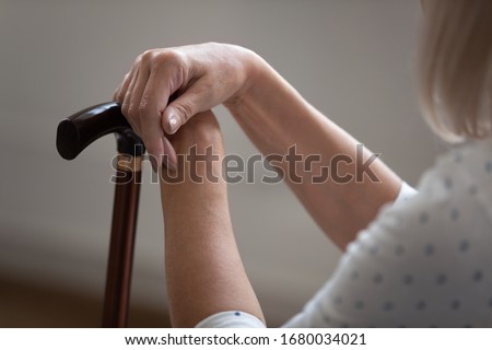 Older retired woman holding hands on wooden cane, close up. Tired mature female pensioner resting after painful walking with stick. Retirement healthcare, rehabilitation, ageing process concept. Royalty-Free Stock Photo #1680034021