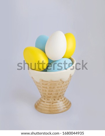 Easter yellow and blue eggs in an ice cream cone on a gray background.