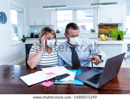 Coronavirus economic recession. Stressed couple with masks in self-isolation over home finances and small business debts during quarantine shutdown. impact of COVID-19 pandemic Global Economy Crisis. Royalty-Free Stock Photo #1680055249