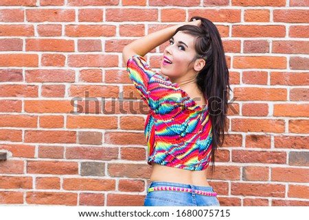 Fashion and urban style concept - Portrait of a beautiful woman in blue jeans against brick wall with copy space