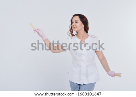 a girl in a white coat with wooden sticks in her hands. the doctor is preparing for waxing. Medicine concept, medical instruments, health care , beauty industry, hair removal, natural material