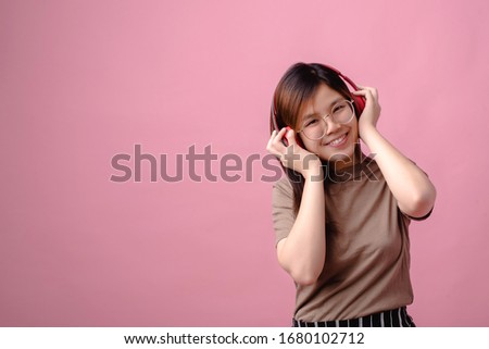
Asian women are listening to headphones happily and relaxed - Pink background - copy space.