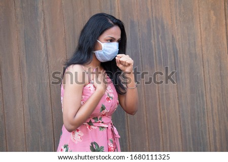 Ill woman using protective face mask as well as fist while coughing to protect others from getting infected from coronavirus pandemic Royalty-Free Stock Photo #1680111325