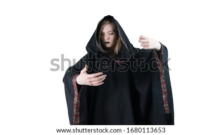 A girl in a black robe, making magic movements. On white background. Witchcraft.