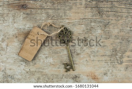 Concept of new life, dream or house with vintage key and mock up clean cardboard tag on wood background