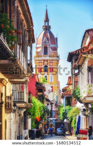 A street in Cartagena, Colombia with a lovely church tower overlooking a street with balconies shrouded in bougainvillia Royalty-Free Stock Photo #1680134512