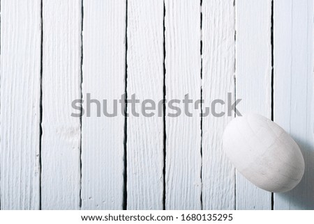 white painted wooden egg on bright wood table background
