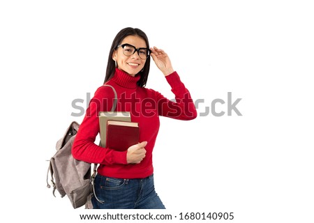 Closeup photo of young woman standing with a backpack, holding books in her hands, and smiling, wearing casual outfit and reading glasses, isolated on white background