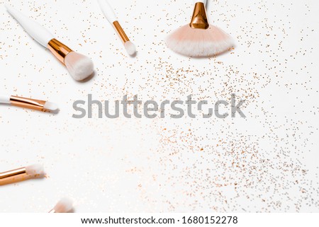 Makeup brushes, hyaluronic acid and golden glitter confetti on white background. Horizontal view copyspace.