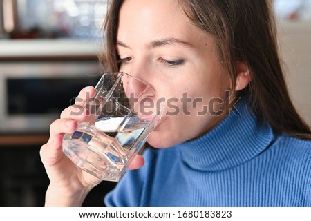 Drink plenty of water from the virus, Covid-19 Pandemic Coronavirus. Girl drinks water from a glass Royalty-Free Stock Photo #1680183823