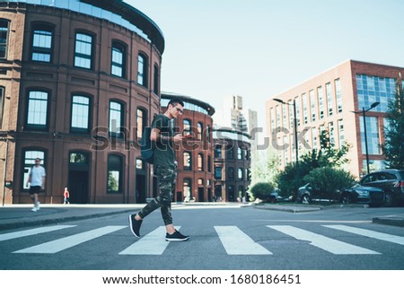 Young Caucasian male student with backpack checking schedule for university lessons on way for study connected to 4g wireless on modern cellphone, millennial guy reading world news on website