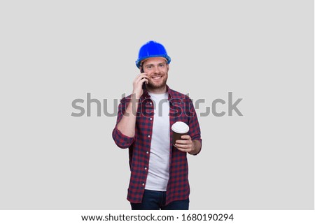 Construction Worker Smiling Talking on the Phone and Holding Coffee To Go Cup Isolated. Blue Helmet