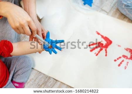 Adorable cute caucasian little blond siblings children enjoy having fun together with mother painting brush and palm at home indoors . Cheerful happy kids smiling drawing masterpiece art picture