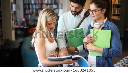 Happy young university students friends studying with books at university