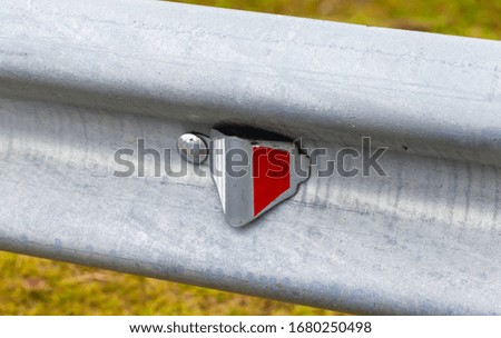 Retro-reflecting optical unit is on a metal guardrail. Highway safety equipment, close-up photo
