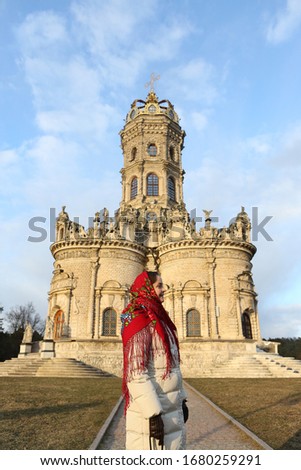 Church of the Sign of the Holy Virgin in Dubrovitsy, Moscow city, Russia (also known as Znamenskaya Church, Church of the Sign of the Blessed Virgin Mary). Russian woman in vintage Pavlovo Posad shawl