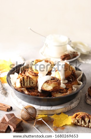 The concept of American cuisine. Pastries and desserts. Cinnabon with cinnamon and white glaze. Buns with cinnamon and cream cheese on a light background. Background image, copy space