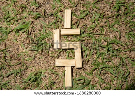 Block of wooden stick on the garden field showing money sign