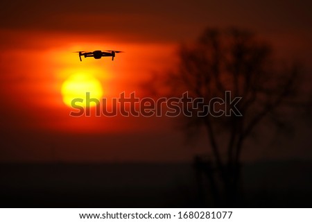 Drone with quadcopter camera at sunset in flight for observation. 4 blade propeller drone. the silhouette of the drone is visible at sunset.