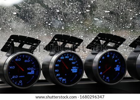 Car racing gauges meter on car console with rain drop on car glass background