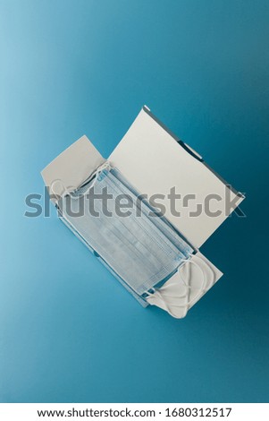 Surgical protective mask. Box of Medical respiratory bandage face Shortage of masks on a blue background. prevention of the spread of virus and pandemic COVID-19.