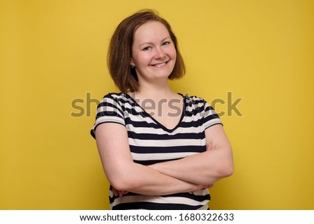 Pretty excited woman with happy smile. Young attractive girl portrait stand folded hands looking at camera smiling isolated over yellow background