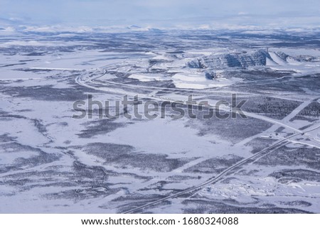 Aerial shot of the snow covered Kiruna area with a road in Lapland in Sweden in winter. At the top right the factories of the LKAB, a large Swedish mining company