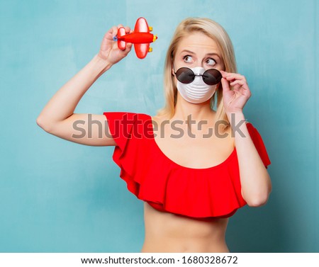 Blonde woman in red bikini and face mask with binoculars on blue background 