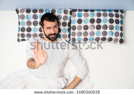 Man in bed in top view making stop gesture