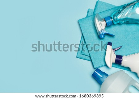 Assorted cleaning products bottles on a light blue background