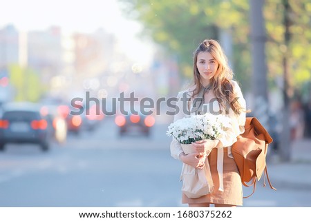 girl with a bunch of flowers walks street cars / urban view, landscape with a model young girl holding flowers