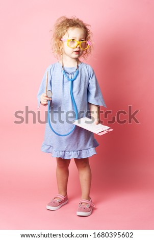 Pediatrics: a little girl in the form of a nurse with glasses and with a stethoscope fills a prescription.