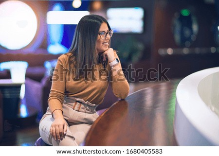 Young beautiful woman smiling happy and confident. Sitting with smile on face leaning on the counter bar at restauran