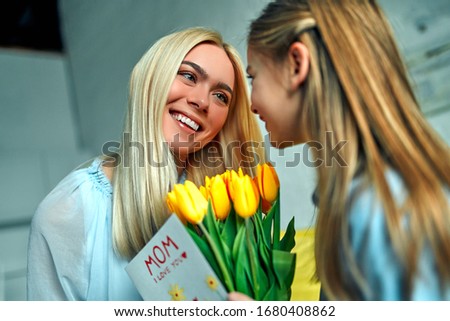 Happy mother's day! Little girl giving a bouquet to her mother. Daughter congratulating mom on beautiful spring flowers on mother's day